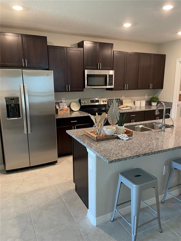 A kitchen features dark wood cabinets, stainless steel appliances, and a granite-topped island — 1541 LANDMARK DRIVE, LAKELAND, FL