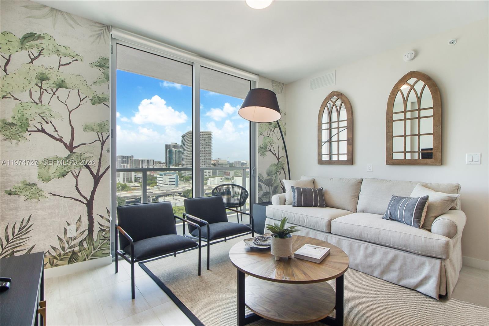 A living room features a sofa, two chairs, a coffee table, and scenic wallpaper — 3900 Biscayne Blvd # 1108, Miami FL 33137, MIAMI, FL