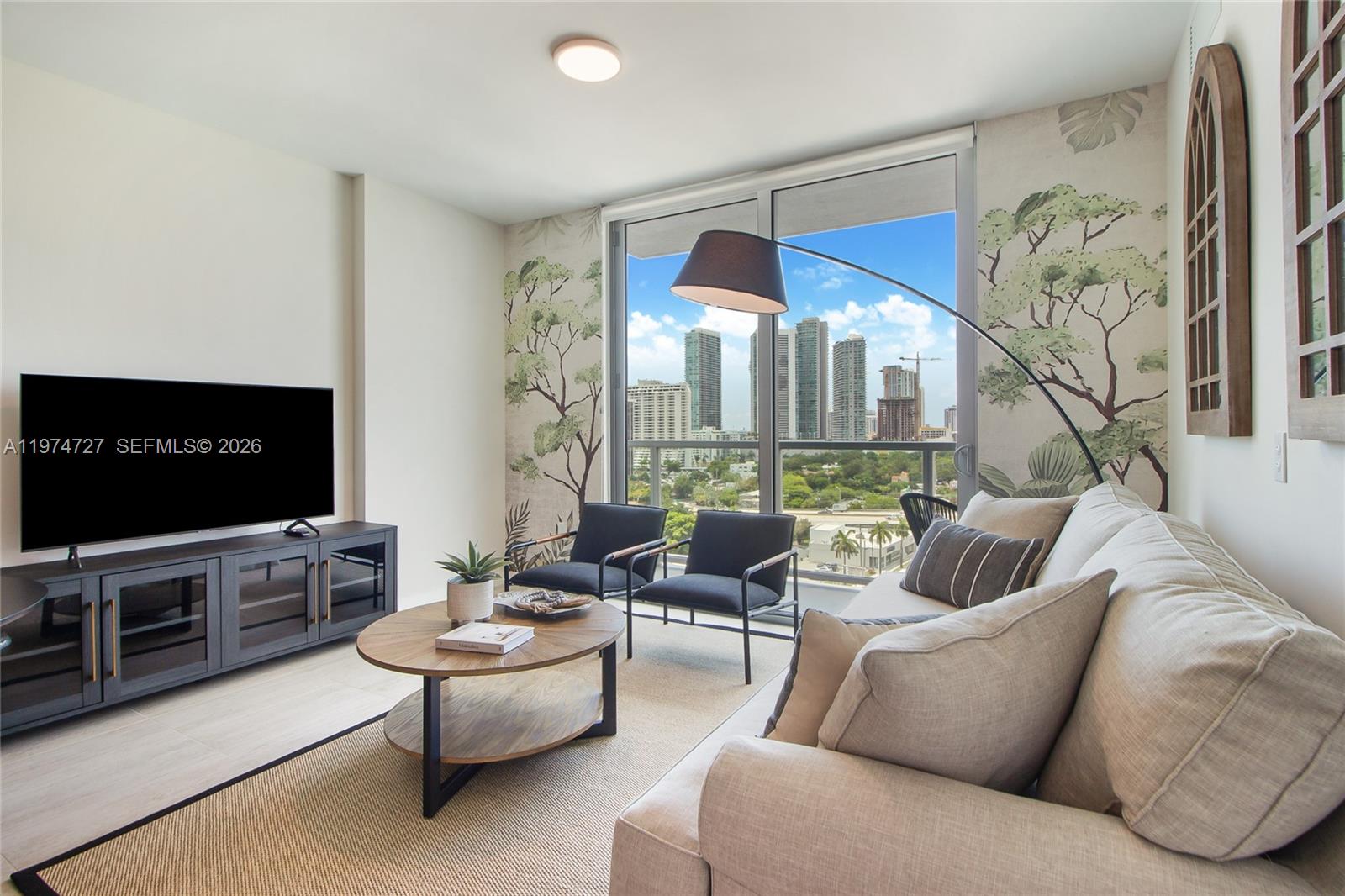 A living room features a television, sofa, two armchairs, a coffee table, and floor-to-ceiling windows — 3900 Biscayne Blvd # 1108, Miami FL 33137, MIAMI, FL