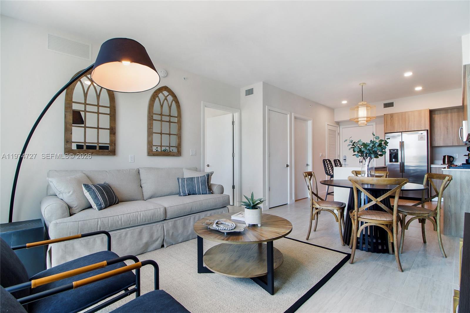 A living room and dining area feature a light gray sofa, round table, and kitchen — 3900 Biscayne Blvd # 1108, Miami FL 33137, MIAMI, FL