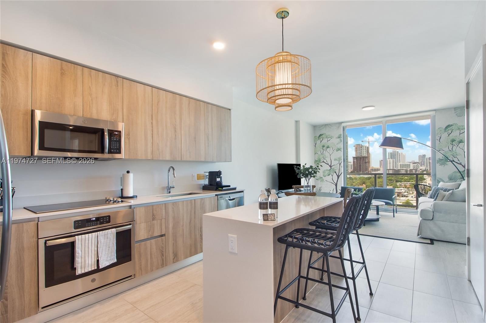A modern kitchen with light wood cabinets and a white island overlooks a city view — 3900 Biscayne Blvd # 1108, Miami FL 33137, MIAMI, FL