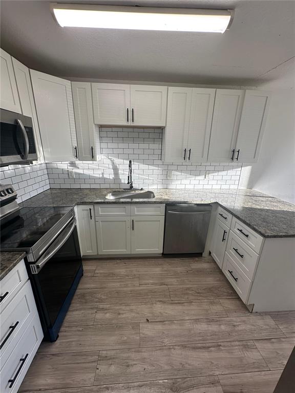 A kitchen features white cabinets, granite countertops, a subway tile backsplash, and stainless steel appliances — 5064 DOWNING STREET UNIT 4, ORLANDO, FL