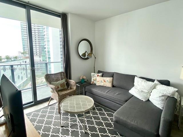 A living room features a gray sectional sofa, a wicker chair, and a round coffee table — 501 NE 31st St # 802, Miami FL 33137, MIAMI, FL