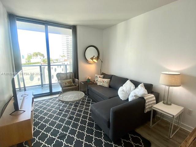 A living room features a gray sectional sofa, a patterned rug, and a balcony view — 501 NE 31st St # 802, Miami FL 33137, MIAMI, FL