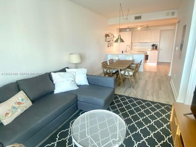 A living room with a grey sectional sofa, a coffee table, and an open kitchen — 501 NE 31st St # 802, Miami FL 33137, MIAMI, FL