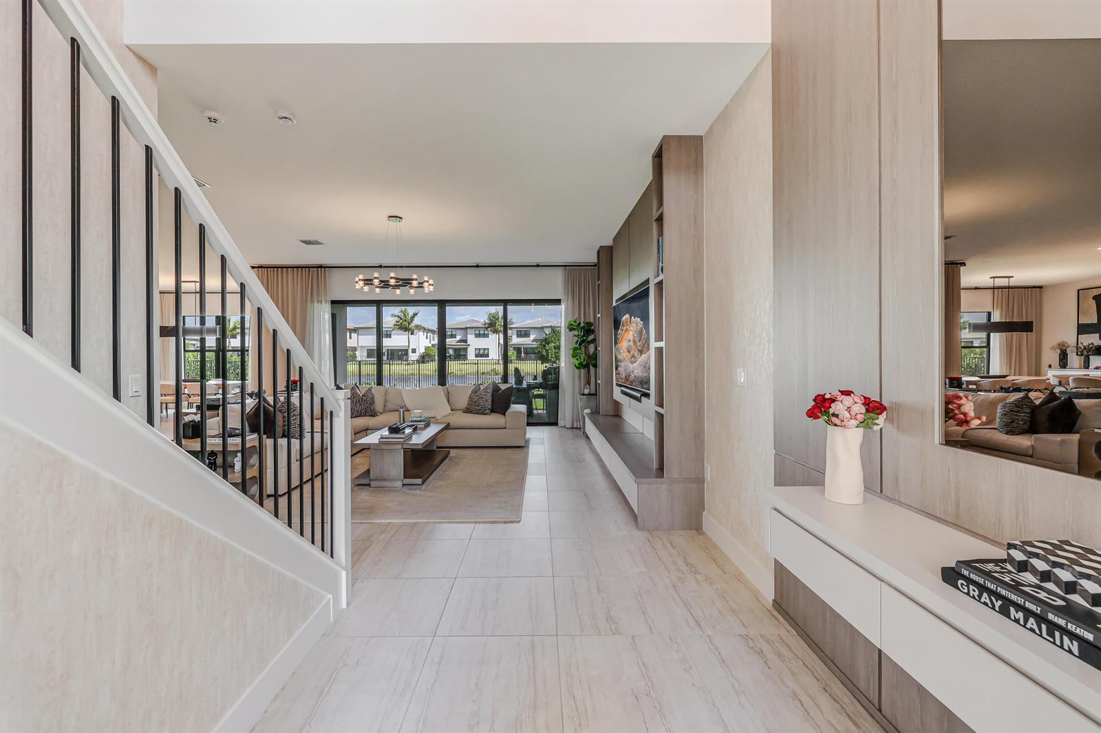 A modern living room features a staircase, light tile flooring, and a large wall unit — 8283 Royal County Down Road, Boca Raton FL 33434, BOCA RATON, FL