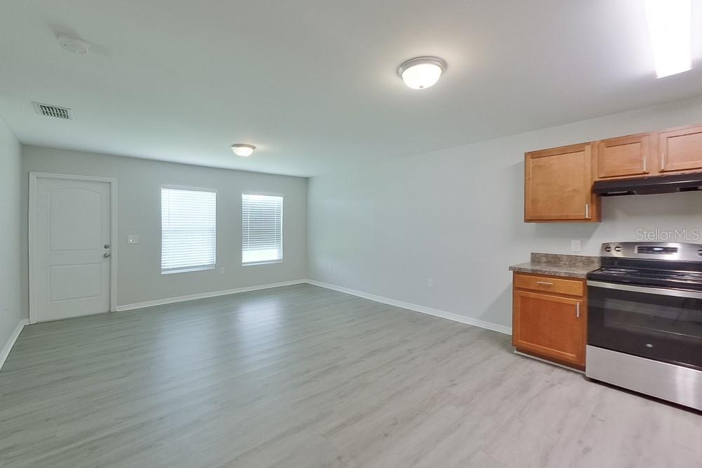 An open-concept kitchen and living area features light gray flooring, white walls, and wood cabinets — 3214 65TH STREET W, LEHIGH ACRES, FL