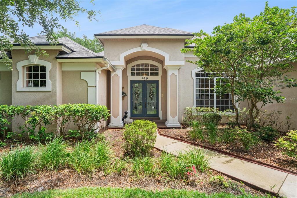 The exterior of a single-story house features a covered entryway with columns and double doors — 418 WOLDUNN CIRCLE, LAKE MARY, FL