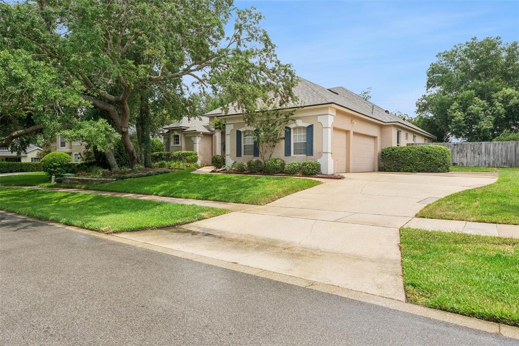 A tan single-story house with a two-car garage and a large tree in the yard — 418 WOLDUNN CIRCLE, LAKE MARY, FL