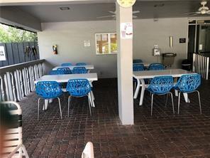 A covered outdoor patio features white tables and blue chairs on a brick-paved floor — 7877 Golf Circle Drive # 211, Margate FL 33063, MARGATE, FL