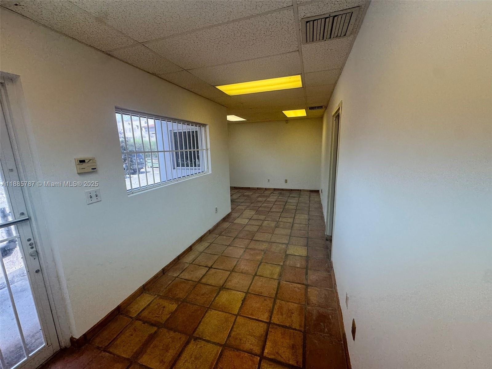 A narrow room features terracotta tile flooring, white walls, a barred window, and drop ceilings — 10849 NW 29th St # 10849, Doral FL 33172, DORAL, FL