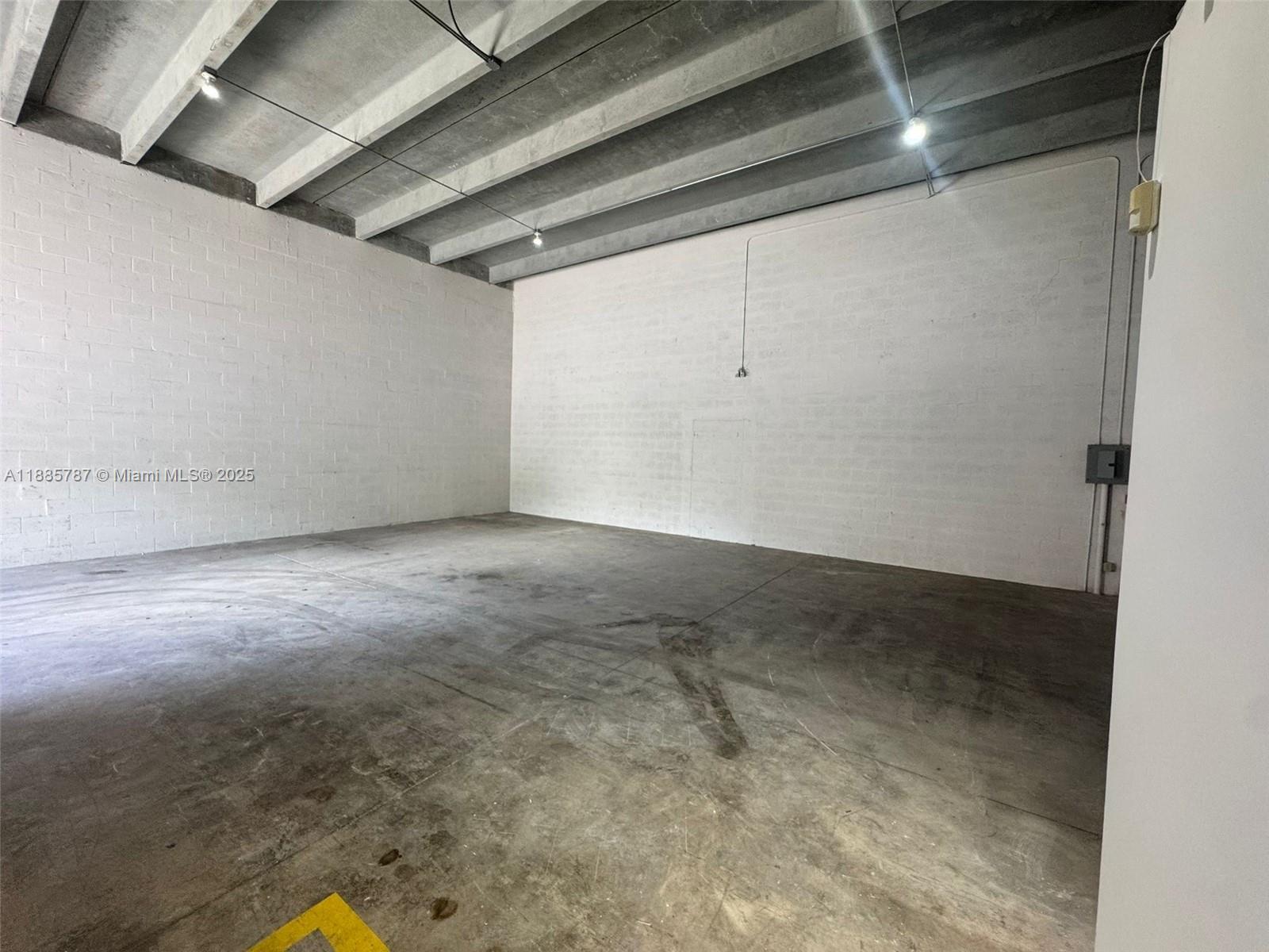An empty industrial space features white block walls, a concrete floor, and exposed ceiling beams — 10849 NW 29th St # 10849, Doral FL 33172, DORAL, FL