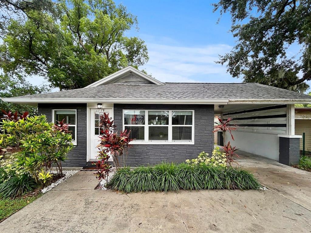 A single-story house with dark gray siding, a white front door, and an attached carport — 1718 LAVON STREET, LAKELAND, FL