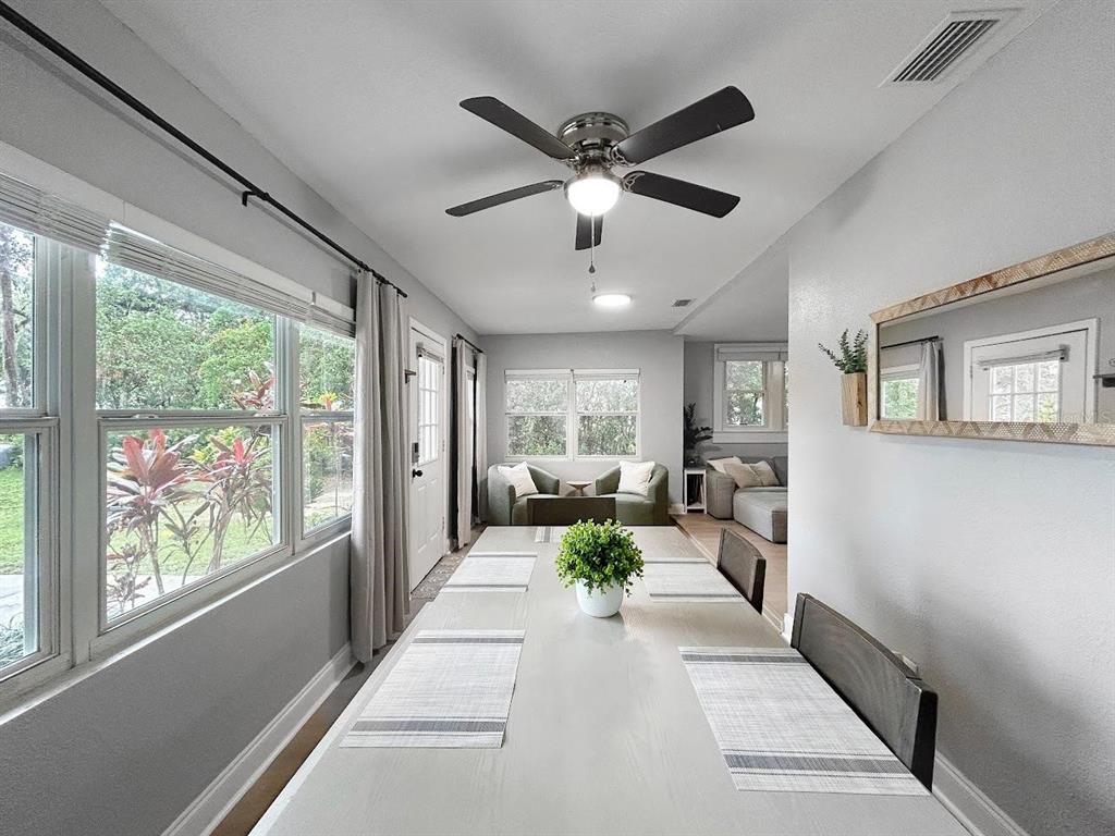A dining room features a long table, a ceiling fan, and large windows with curtains — 1718 LAVON STREET, LAKELAND, FL