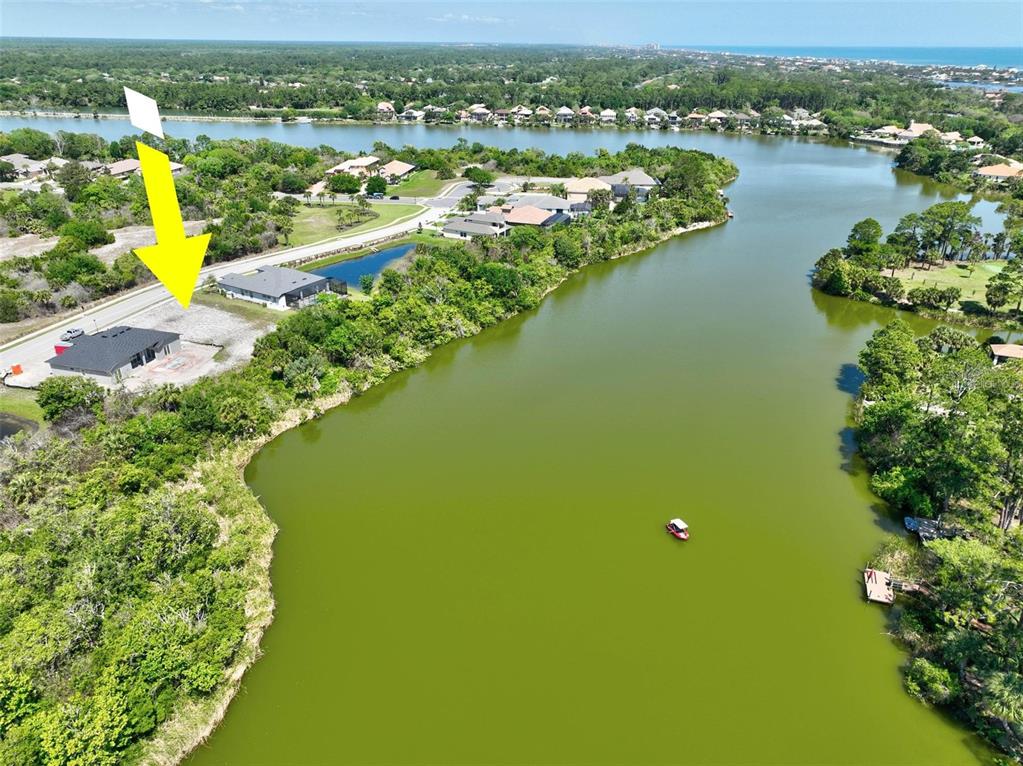An aerial view shows a house under construction next to a large lake — 128 N LAKEWALK DRIVE, PALM COAST, FL