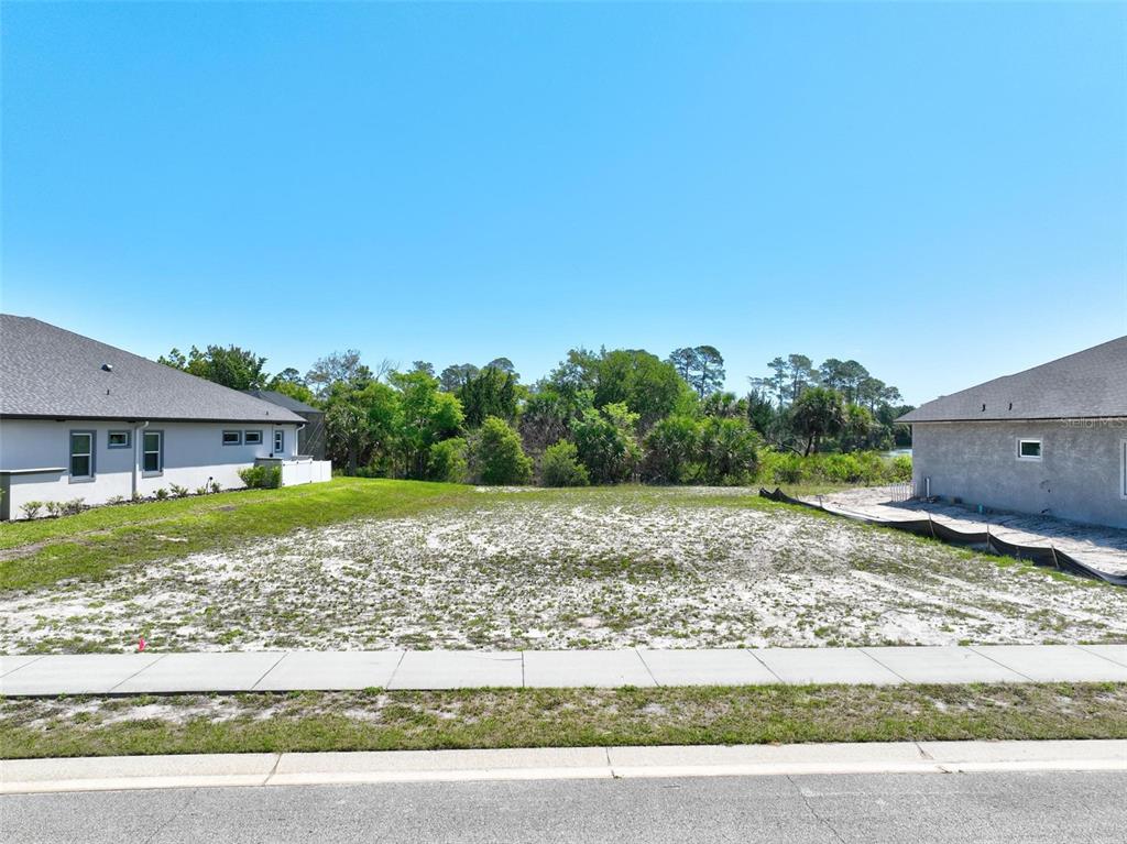 A vacant residential lot sits between two houses with a sidewalk in the foreground — 128 N LAKEWALK DRIVE, PALM COAST, FL