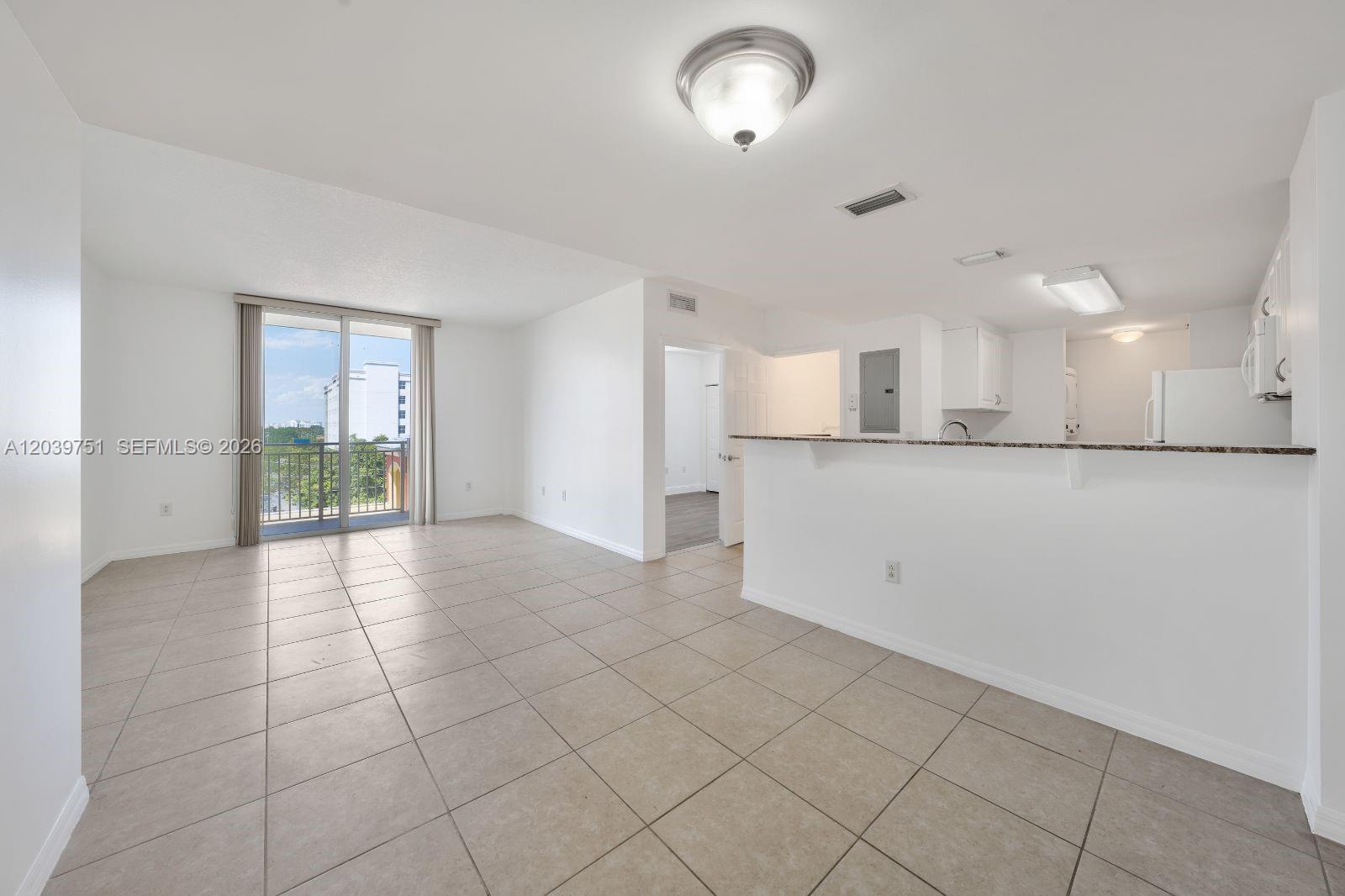 A bright living room features tile flooring, a breakfast bar, and a sliding glass door — 215 SW 42nd Ave # 507, Miami FL 33134, MIAMI, FL