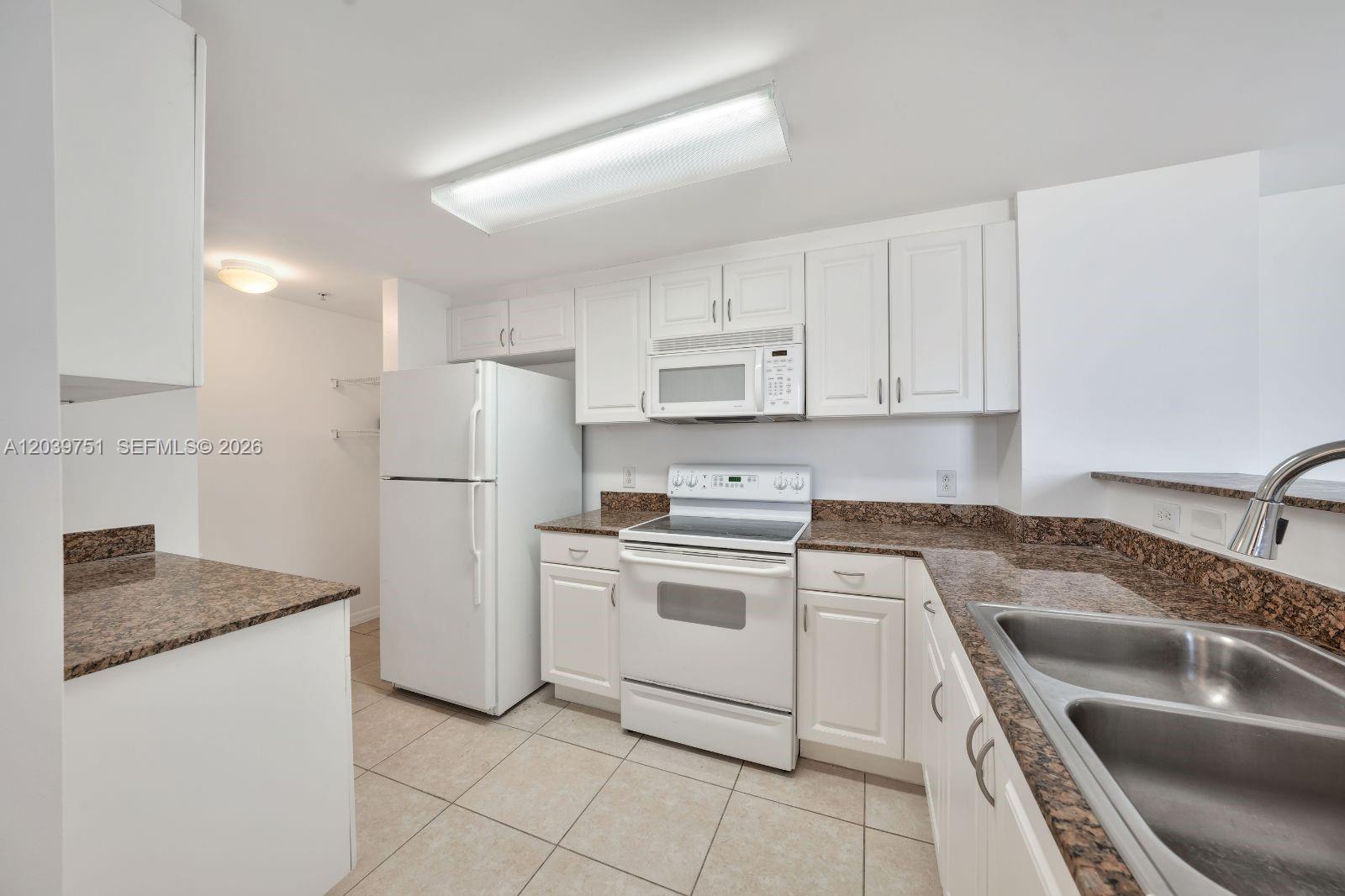 A kitchen features white cabinets, granite countertops, white appliances, and light-colored tile flooring — 215 SW 42nd Ave # 507, Miami FL 33134, MIAMI, FL