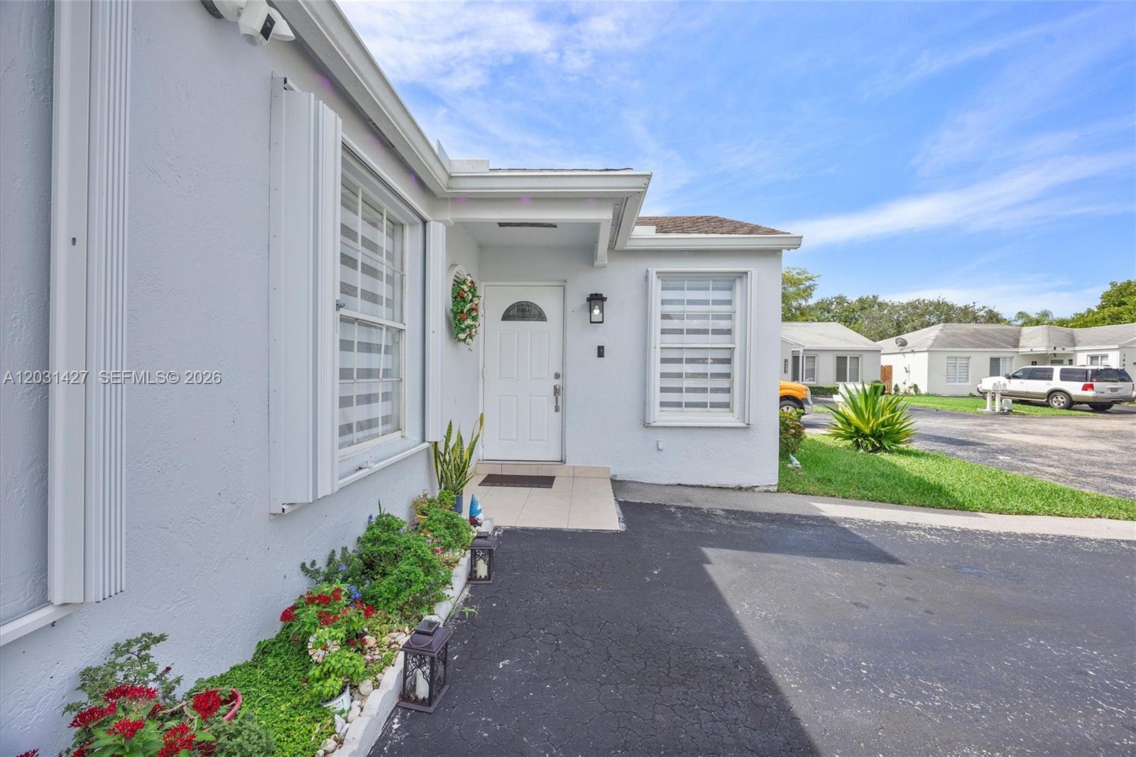 The exterior of a white house features a front door, windows, and a paved driveway — 14623 SW 125th Pl, Miami FL 33186, MIAMI, FL