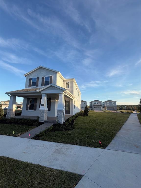 A two-story house with light siding and stone accents features a front porch and walkway — 1389 LUMPINI STREET, ST CLOUD, FL