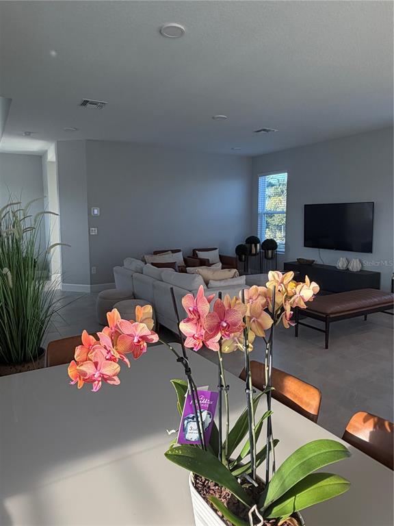A dining area with an orchid centerpiece overlooks a living room with a sectional sofa — 1389 LUMPINI STREET, ST CLOUD, FL