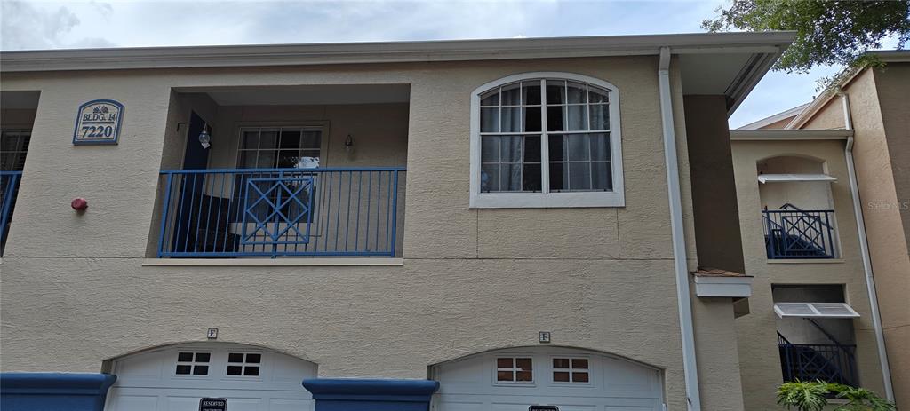 The exterior of a two-story apartment building features balconies, arched windows, and two garage doors — 7220 WESTPOINTE BLVD UNIT 1429, ORLANDO, FL