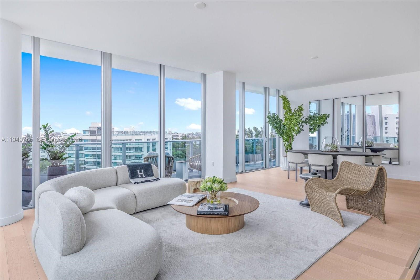 A bright living and dining area features floor-to-ceiling windows, light wood floors, and modern furniture — 9201 E Bay Harbor Dr, Bay Harbor Islands FL 33154, BAY HARBOR ISLANDS, FL