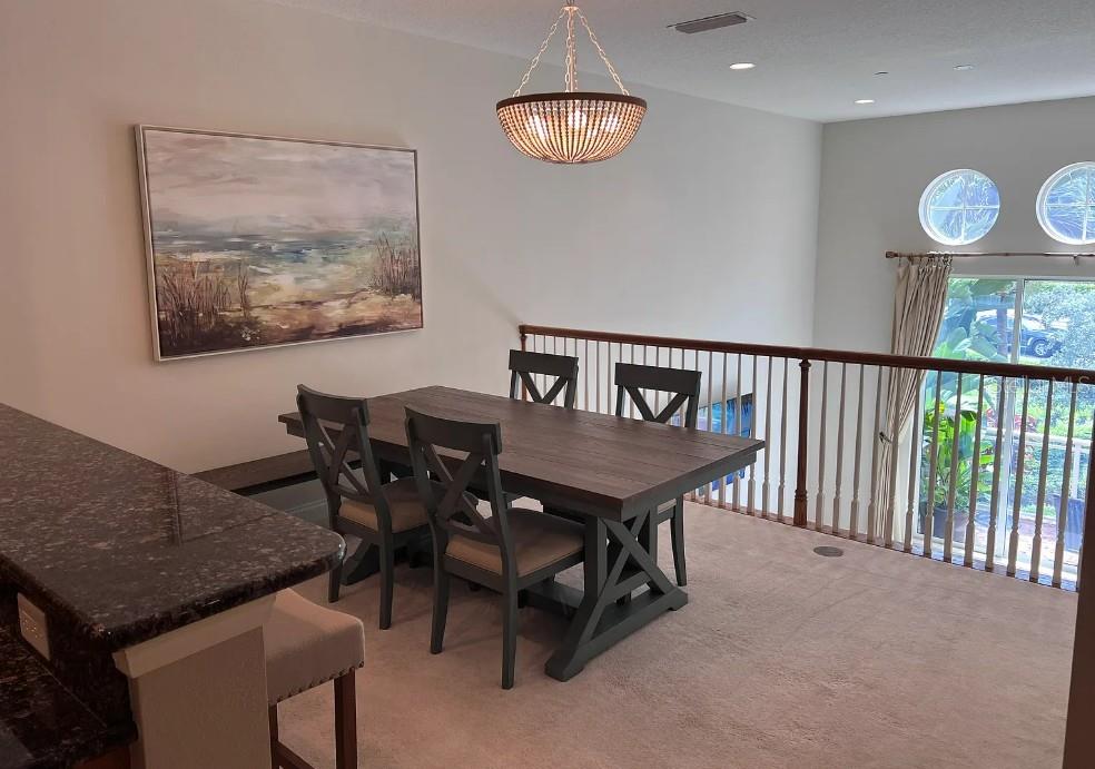 A dining area features a wooden table, chairs, and a chandelier overlooking a lower level — 505 MANDALAY AVENUE UNIT 72, CLEARWATER BEACH, FL