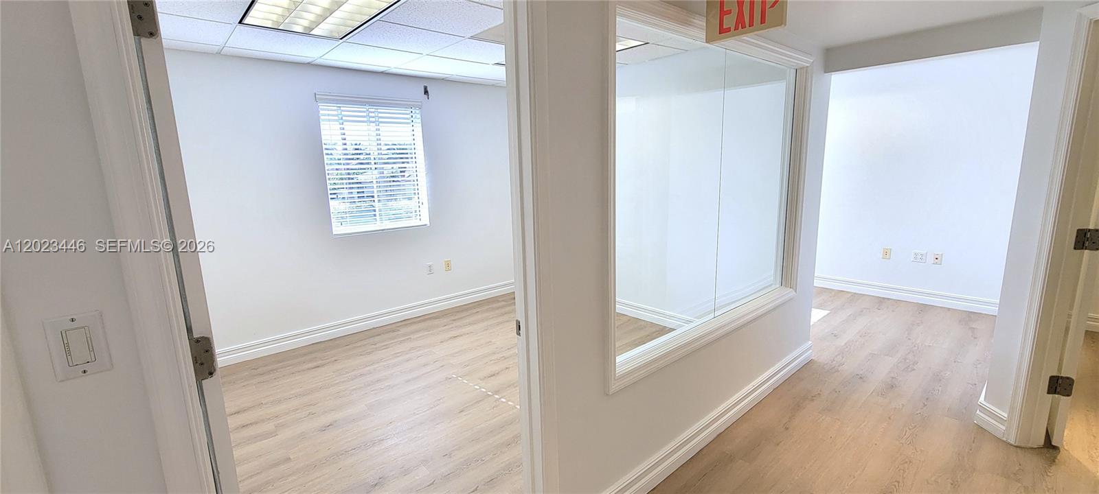 An office space features light wood-look flooring, white walls, and a glass partition wall — 7765 SW 87th Ave # 207A, Miami FL 33173, MIAMI, FL