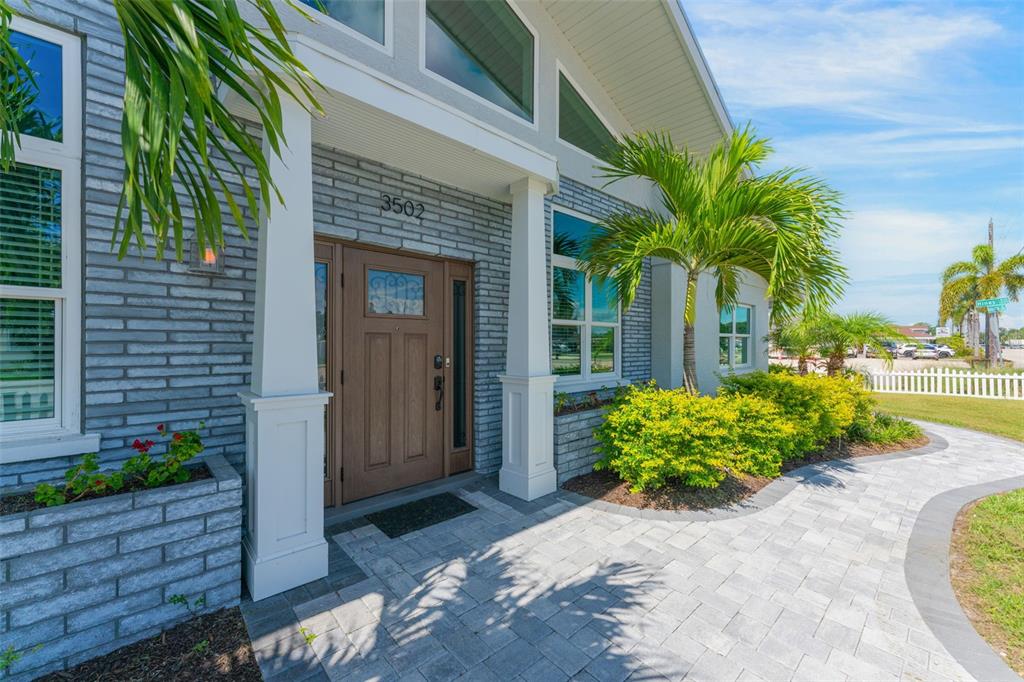 A gray brick house features a brown front door, white columns, and a paved walkway — 3502 BAHIA VISTA STREET, SARASOTA, FL