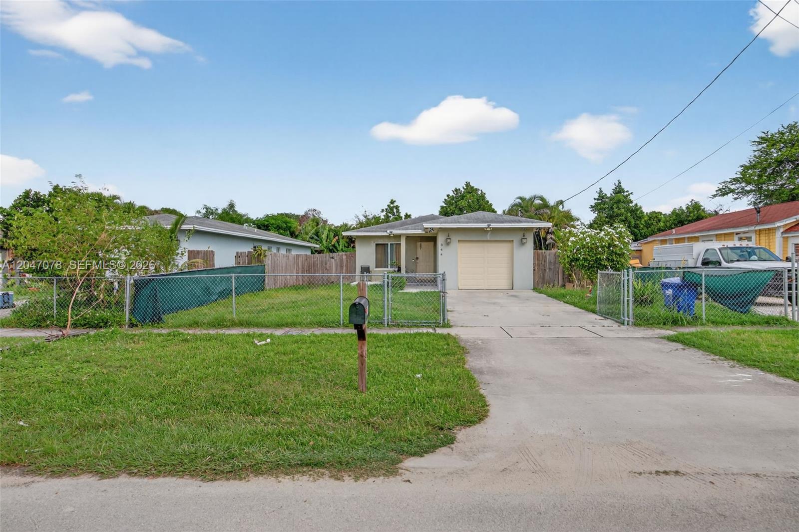 A single-story house with a beige exterior, a one-car garage, and a chain-link fenced yard — 344 SW 3rd St, Florida City FL 33034, FLORIDA CITY, FL