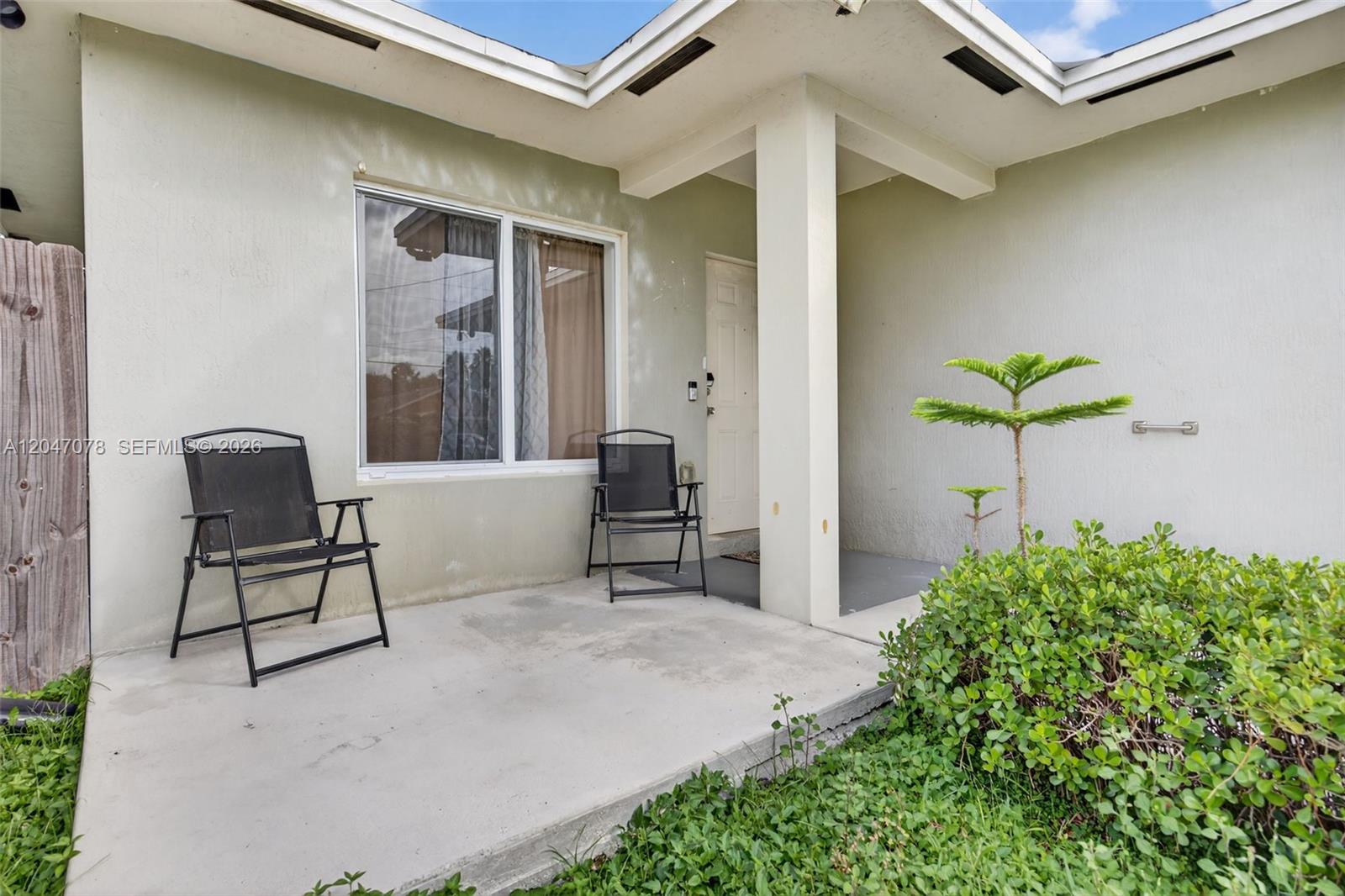 A concrete patio features two black folding chairs in front of a house exterior — 344 SW 3rd St, Florida City FL 33034, FLORIDA CITY, FL
