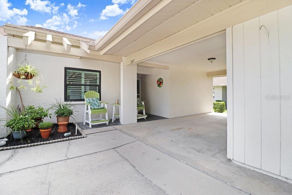 A concrete driveway leads to a covered carport entrance with a small garden bed nearby — 9247 GOLF VIEW DRIVE UNIT 9247, NEW PORT RICHEY, FL