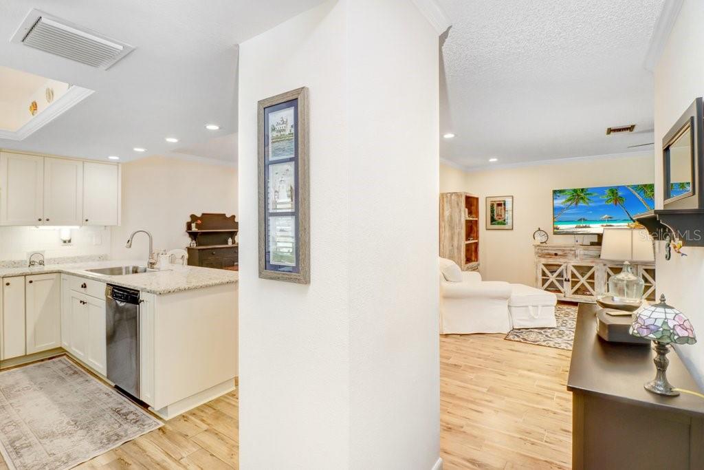 A kitchen with white cabinets and granite countertops opens into a living area with flooring — 9247 GOLF VIEW DRIVE UNIT 9247, NEW PORT RICHEY, FL