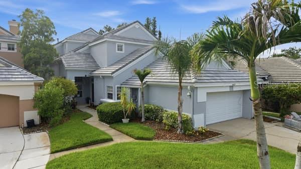 A two-story light gray house with a tiled roof, a garage, and a front lawn — 4415 AVENUE CANNES, LUTZ, FL