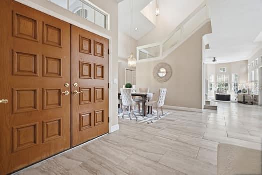 A foyer with wood double doors opens into a dining area with tile flooring — 4415 AVENUE CANNES, LUTZ, FL