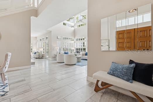 A bright entryway with light tile floors leads into a spacious living room with high ceilings — 4415 AVENUE CANNES, LUTZ, FL