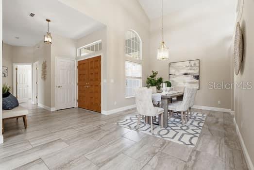 A dining area with a table and chairs sits near a wooden double-door entryway — 4415 AVENUE CANNES, LUTZ, FL