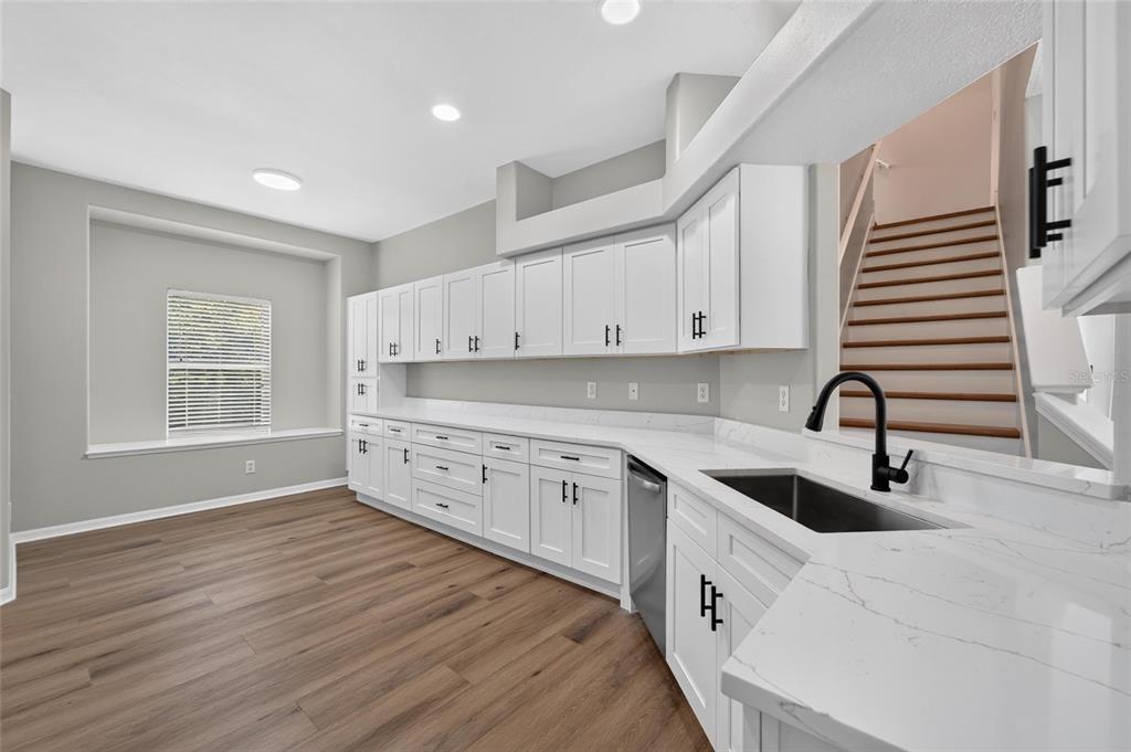 A kitchen with white cabinets, marble-look countertops, a black faucet, and wood-style flooring — 21744 WAVERLY SHORES LANE, LAND O LAKES, FL