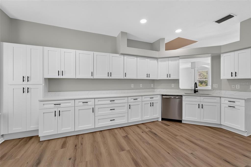 A kitchen features white shaker cabinets, quartz countertops, stainless steel appliances, and wood-look flooring — 21744 WAVERLY SHORES LANE, LAND O LAKES, FL