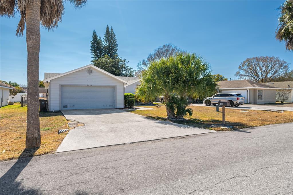 A single-story house with a concrete driveway, a garage, and palm trees in the yard — 3406 FOX RIDGE STREET, WINTER HAVEN, FL