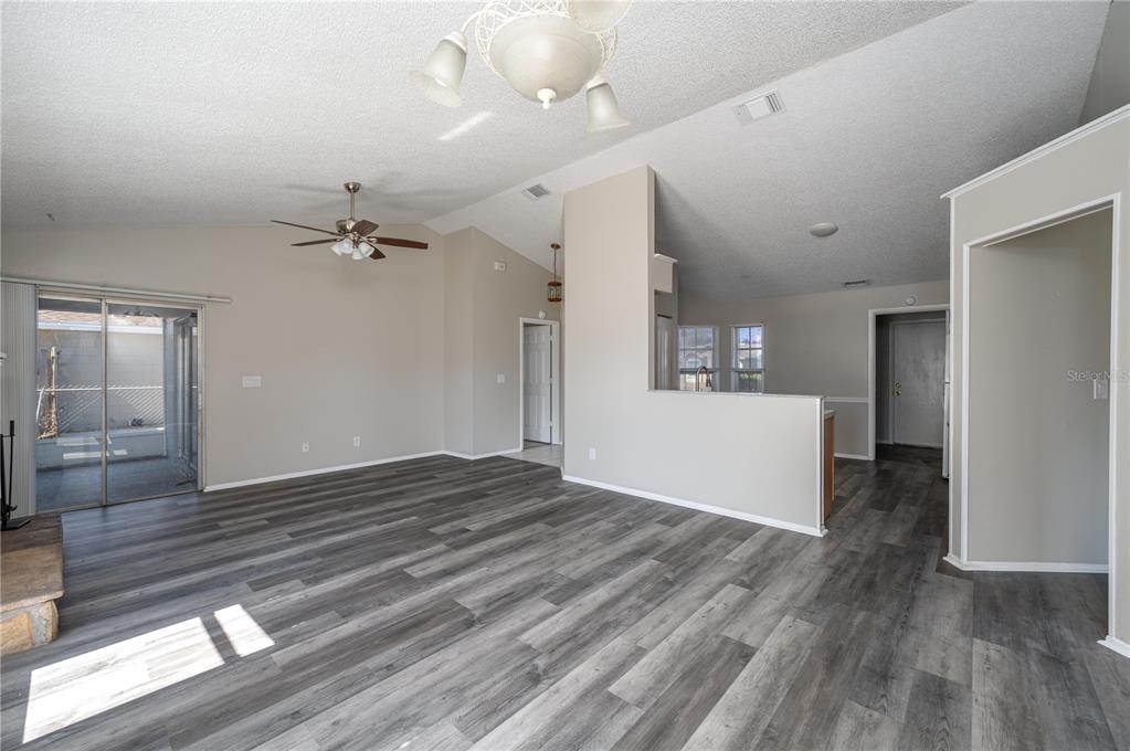 An open living area features gray wood-look flooring, a vaulted ceiling, and a ceiling fan — 3406 FOX RIDGE STREET, WINTER HAVEN, FL
