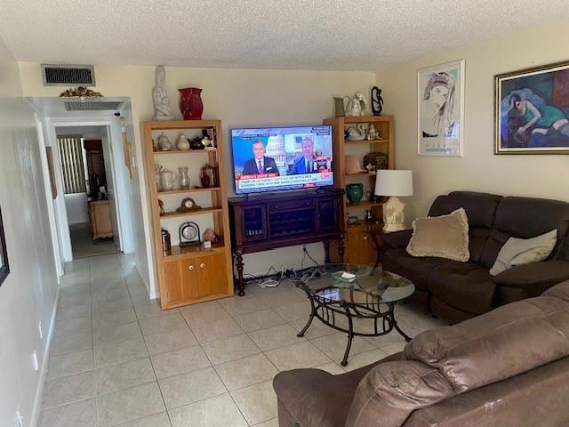 A living room features tile flooring, a television on a console, and brown leather furniture — 117 Brighton C # 117, Boca Raton FL 33434, BOCA RATON, FL