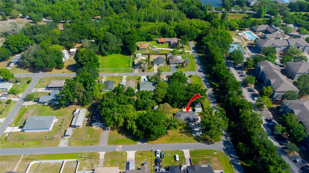 An aerial view shows a residential neighborhood with a red arrow pointing to a house — 7716 E COMANCHE AVENUE, TAMPA, FL