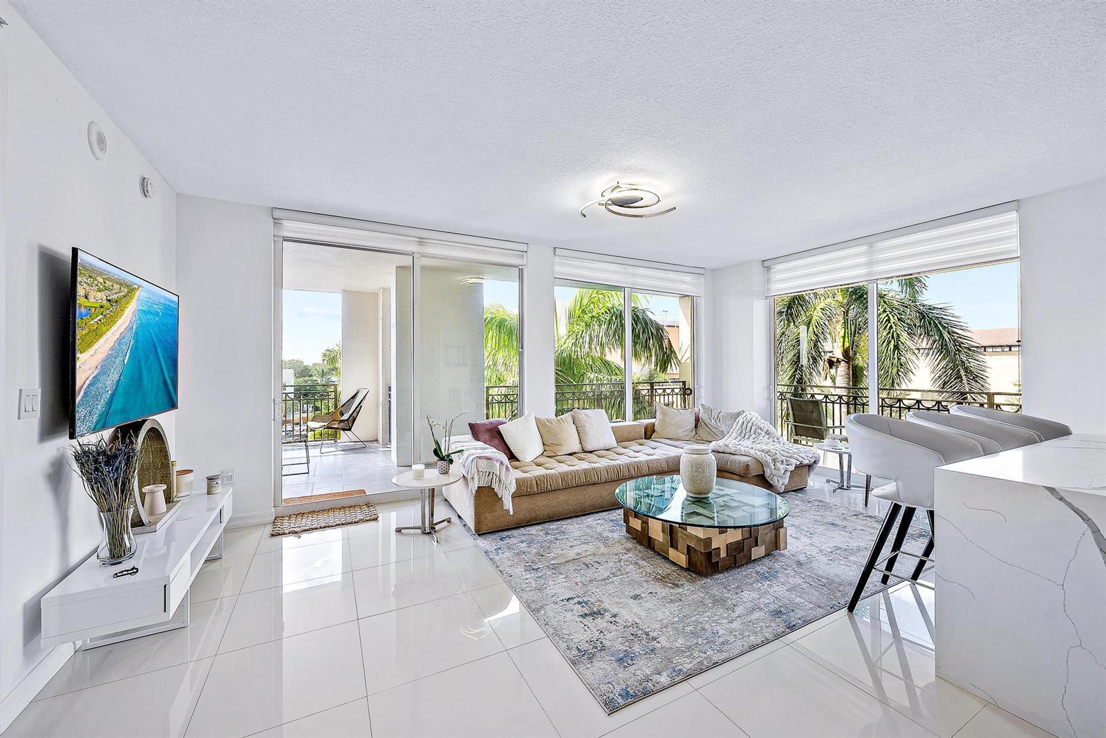 A bright living room features white tile floors, a sectional sofa, and floor-to-ceiling glass doors — 550 Okeechobee Boulevard # 422, West Palm Beach FL 33401, WEST PALM BEACH, FL