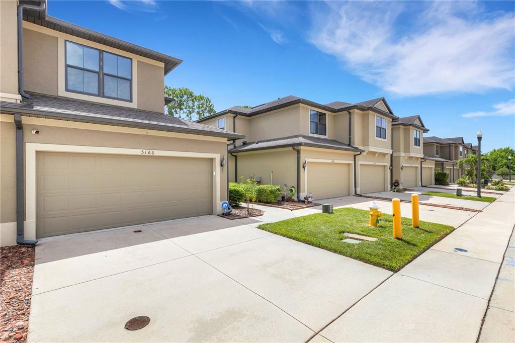 A row of two-story townhouses with beige stucco exteriors and attached garages — 5166 BAY ISLE CIRCLE, CLEARWATER, FL