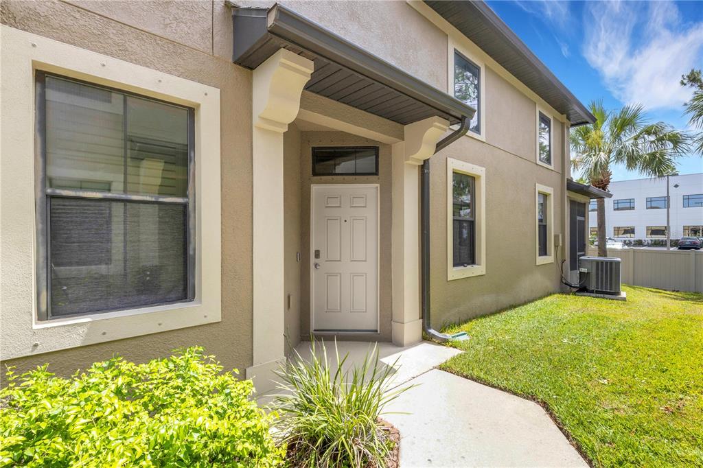 A tan two-story building exterior features a white front door under a small covered porch — 5166 BAY ISLE CIRCLE, CLEARWATER, FL