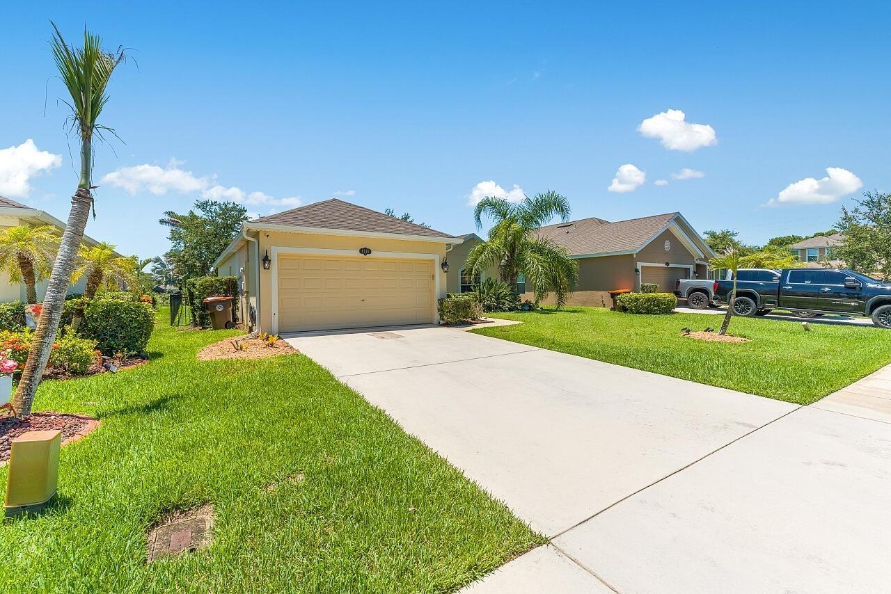 A single-story suburban house with a tan exterior, a two-car garage, and a concrete driveway — 8110 Westfield Circle, Vero Beach FL 32966, VERO BEACH, FL