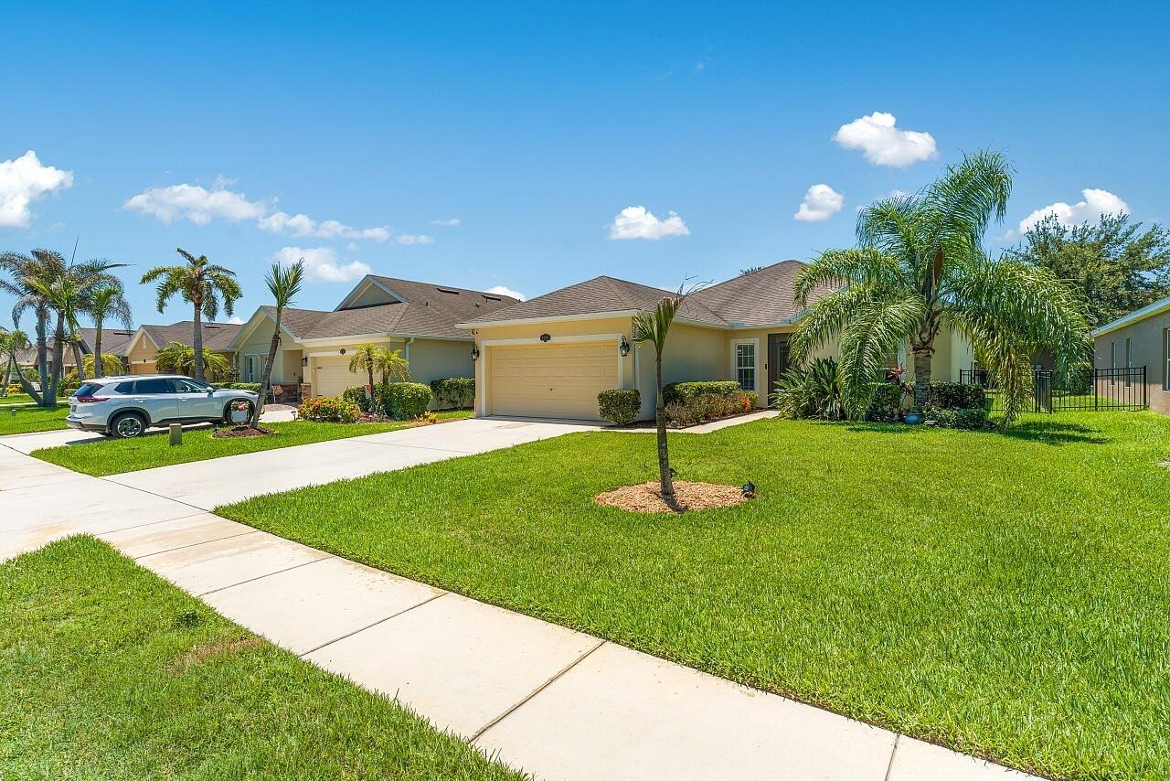 A single-story yellow house with a two-car garage and palm trees in the front yard — 8110 Westfield Circle, Vero Beach FL 32966, VERO BEACH, FL