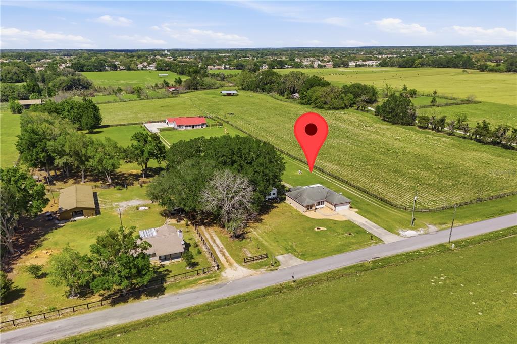 An aerial view shows a house with a red pin on a rural property — 7411 SE 180TH STREET, OXFORD, FL